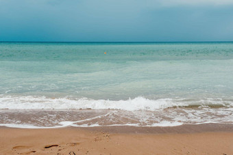 阴天空多雨的一天泡沫波滚动金沙子海滩<strong>低温</strong>暖的太阳光假期娱乐概念摘要航海夏天海洋日落自然