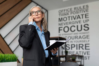 成熟的成人女经济学家灰色的头发说话电话办公室