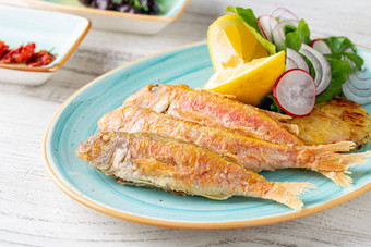 美味的烤红色的鲻鱼鱼配菜柠檬绿色洋葱