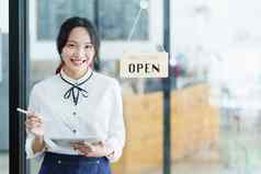 开始开放小业务年轻的亚洲女人显示微笑脸持有平板电脑围裙站前面咖啡商店酒吧计数器业务老板餐厅咖啡馆概念