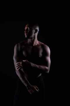 运动非洲美国男人。袒胸大肌肉黑暗背景工作室