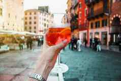 女手玻璃橙色鸡尾酒斯普利茨建筑阳光明媚的一天维罗纳意大利