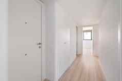 狭窄的白色走廊门入口房间前提休息房间窗口阳光明媚的一边概念极简主义设计公寓