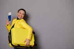 惊人的微笑女人旅游旅行在国外假期携带时尚的黄色的手提箱登机通过