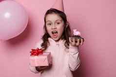 可爱的孩子生日女孩粉红色的节日他摆姿势礼物盒子蛋糕孤立的颜色背景