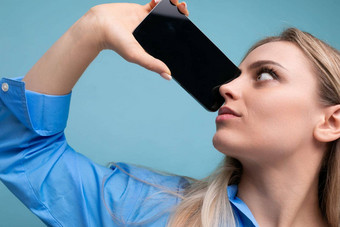 欧洲金发碧眼的女孩持有智能手机屏幕模型网络页面脸蓝色的背景