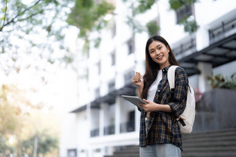 女大学学生幸福的持有笔记本电脑在户外学校校园太阳地平线温暖的光