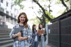 可爱的亚洲女孩学生持有书移动PC校园背景集团学生