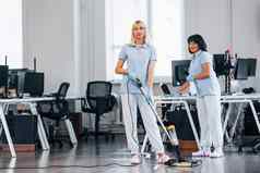 女人真空更清洁的集团工人清洁现代办公室白天