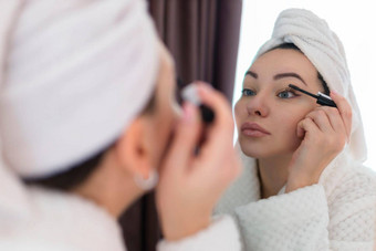 女人适用于黑色的睫毛膏睫毛化妆刷年轻的美丽的女人应用睫毛膏化妆眼睛浴室