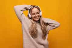 快乐的欧洲年轻的女人享受冥想耳机黄色的背景