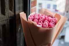 美丽的粉红色的郁金香花束包装纸窗台上
