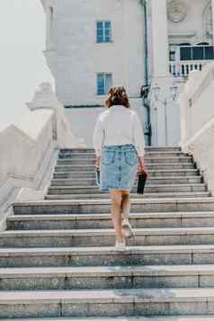 女人楼梯城市业务女人白色衬衫牛仔布裙子走步骤古老的建筑城市