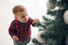 可爱的男孩节日衣服在室内圣诞节树一年时间