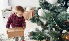 可爱的男孩节日衣服在室内圣诞节树一年时间