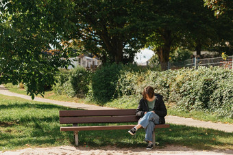 快乐女孩聪明的电话街坐着板凳上美丽的女孩坐着板凳上时尚生活风格电话写消息社会网络阳光明媚的一天公园放松工作业务女人
