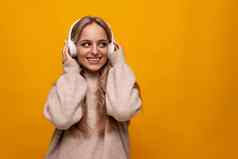 快乐的欧洲年轻的女人享受冥想耳机黄色的背景