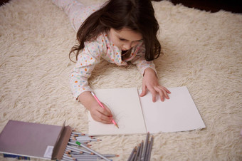 视图高加索人可爱的婴儿女孩时尚的睡衣画图片色彩斑斓的铅笔在室内