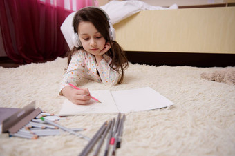 有才华的孩子女孩听音乐耳机吸引了图片铅笔说谎地毯卧室