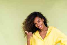 美丽的非洲美国女人休闲衬衫绿色背景快乐积极的兴奋点手指左