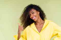 美丽的非洲美国女人休闲衬衫绿色背景快乐积极的兴奋点手指左