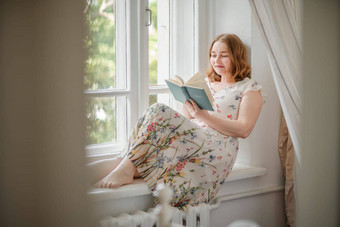 中年女人奶油衣服坐在神秘的窗口窗台上绿色树