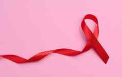 丝绸红色的丝带形式弓粉红色的背景象征战斗艾滋病标志团结支持