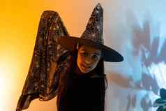 漂亮的年轻的女巫万圣节庆祝活动肖像可爱的十几岁的女孩摆姿势工作室女巫的服装魔法魔杖手混合色彩斑斓的照明
