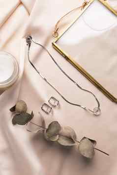 极简主义几何银项链圆耳环丝绸背景现代珠宝珠宝手使