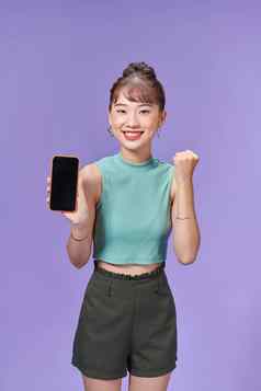 年轻的亚洲女人持有电话快乐的脸紫色的背景