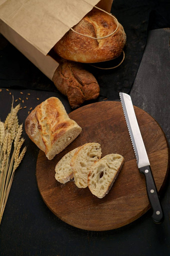 粮食面包把厨房木板刀减少新鲜烤黑麦面包木董事会新鲜的面包表格特写镜头新鲜的面包厨房表格