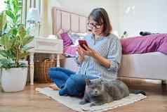 女坐着地板上智能手机宠物猫说谎老板