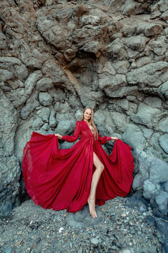 红色的衣服岩石女人金发女郎流动头发长流动红色的衣服站岩石火山起源旅行概念照片会话海