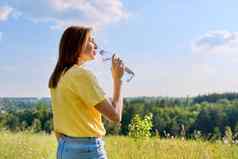 热阳光明媚的夏天渴了成人女人喝水瓶自然