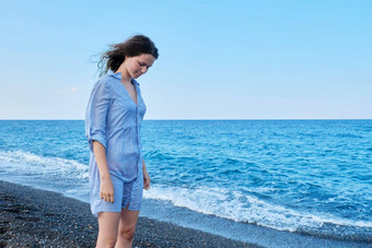 年轻的美丽的女人蓝色的衬衫湿头发海滩