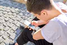 男孩少年年智能手机坐着街夏天城市