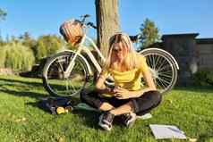 十几岁的学生耳机智能手机自行车坐着公园