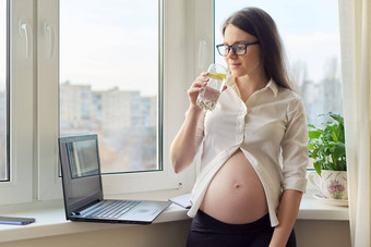 年轻的怀孕了女人喝柠檬<strong>水站</strong>窗口
