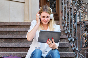 年轻的女人耳机数字平板电脑放松坐着步骤城市
