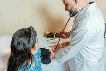 营养学家测量血压力病人测量血压力病人办公室营养学家男人。测量血压力女病人办公室