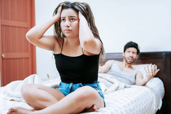 年轻的夫妇争论坐着床上概念夫妇问题床上心烦意乱女人丈夫坐着床上妻子争论丈夫床上