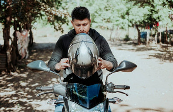 男人。摩托车把头盔骑摩托车的人把安全头盔骑摩托车的人摩托车安全概念年轻的骑摩托车的人男人。把安全头盔
