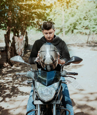 骑摩托车的人摩托车安全概念年轻的骑摩托车的人男人。把安全头盔男人。摩托车把头盔骑摩托车的人把安全头盔