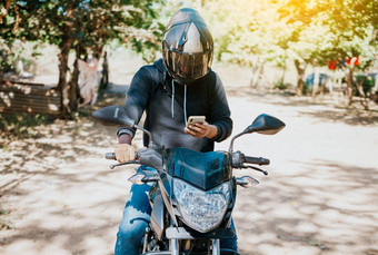 男人。摩托车发短信开车骑摩托车的人摩托车细胞电话在户外概念心烦意乱骑摩托车的人细胞电话