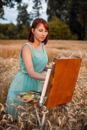 年轻的女孩绘画场黑麦日落