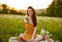 快乐红色头发的人女人坐着洋甘菊场格子莲花位置持有花手微笑相机