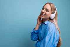 特写镜头欧洲女孩无线大耳机休闲装享受放松音乐应用程序蓝色的背景