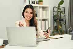 快乐的亚洲女人工人持有移动电话沟通在线看网络研讨会移动PC