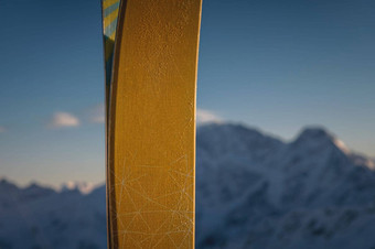 特写镜头滑雪板站背景模糊的白雪覆盖的陡峭的山特写镜头部分滑雪