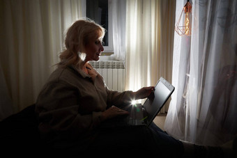 轮廓影子成人成熟的女人年移动PC笔记本电脑温暖的毛衣黑暗平静舒适的晚上大气房间室内窗帘小灵特